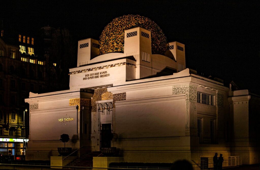 Vienna Secession building with a white facade, gold decorative elements, and a prominent gilded dome composed of laurel leaves. 